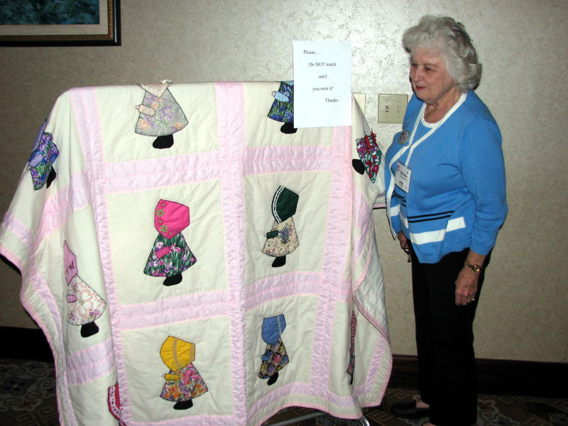 Nelda Moore admires Kitty Lack's  bonnet girl quilt donated for the raffle